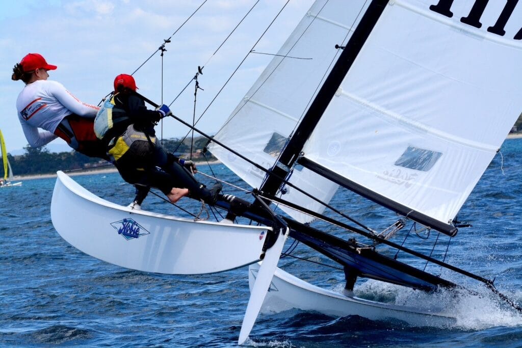 Hobie 16 i full fart med to i trapez – en av verdens mest ikoniske katamaraner, kjent for sin balanse mellom fart og kontroll.